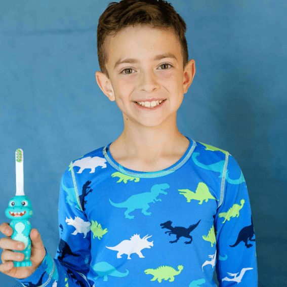 A child holding the Brushy the Brushasaurus toothbrush