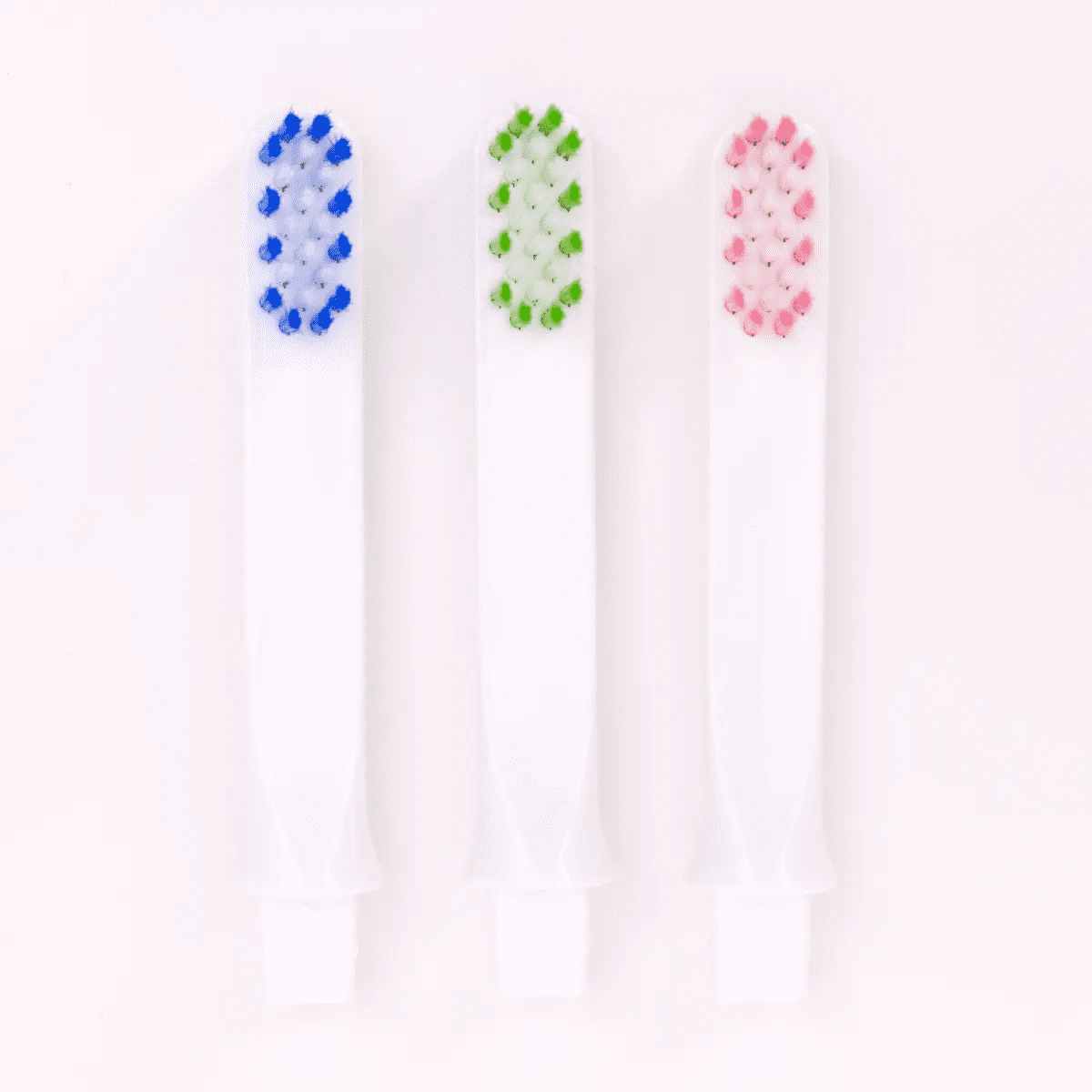 Three differently colored replacement toothbrushes on a white background