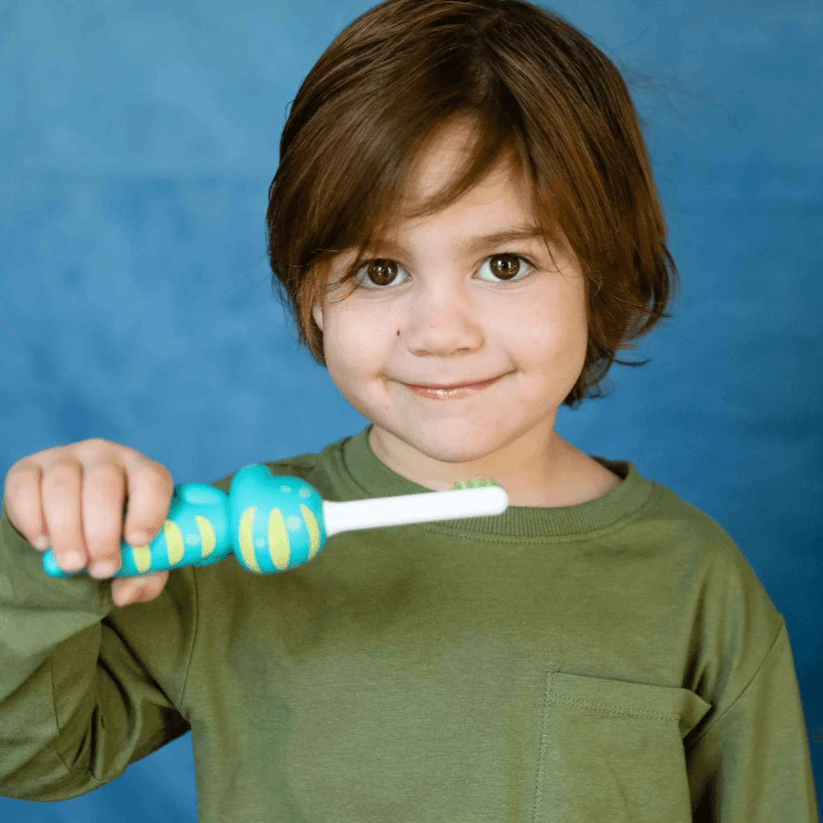 A young child gripping a Brushy the Brushasaurus toothbrush