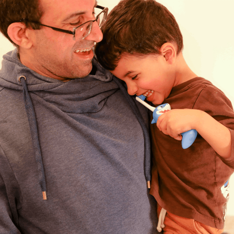 A demonstration of a man and a boy using Chompers the Shark toothbrush